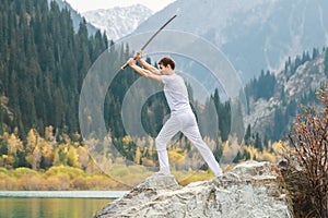 A man holds a Japanese sword katana above his head. Training combat skills