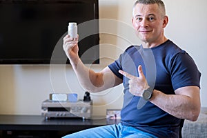 A man holds a jar in his hand, smiling, pointing to a medicine that helped cure a heart ailment.