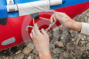 man holds knot in his hands and ties rope aboard boat, ship or yacht