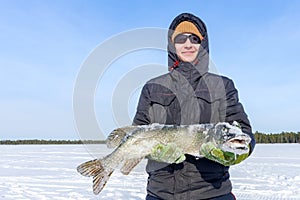 Man holds a large fish pike in winter. Winter fishing catch trophy outdoor activities hobby