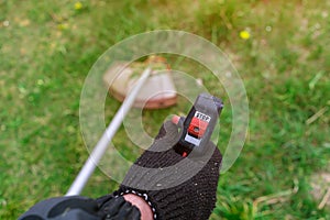 A man holds a lawn mower for the handle