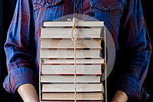 A man holds many books tied with a rope