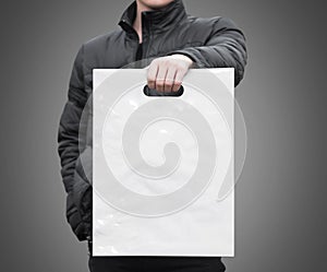 A man holds a mockup white plastic bag. A man with a package on isolated background