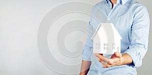 A man holds a model of a house in his hands. Home insurance concept. Loan for the purchase of construction of a house.