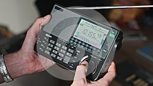 Man Holds Modern Portable Radio With Digital LCD Scale and Scans Radio Stations
