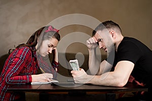 Man holds money and watches wife calculate the budget. financial difficulties