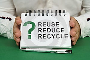 A man holds a notepad in his hands with the inscription - Reuse Reduce Recycle