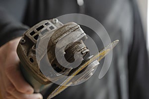 A man holds out an angle grinder into the camera