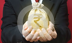A man holds out a indian rupee money bag. Budget management, tax collection. Trade, economics. Granting financing business project