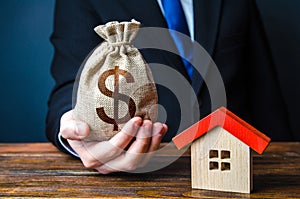 Man holds out a money bag near the house. Bank approval for issuing a mortgage loan. Favorable terms and conditions, low interest