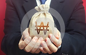 Man holds out a south korean won money bag. Budget management, collect taxes. Financial crisis support, benefits, subsidies.