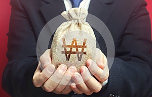 Man holds out a south korean won money bag. Budget management, collect taxes. Financial crisis support, benefits, subsidies. photo