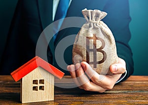 Man holds out a thai baht bag near the house. Bank approval for issuing a mortgage loan. Property appraisal. Home purchase, invest