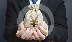 A man holds out a yen yuan money bag. Trade, economics. Granting financing business project or education. Provision cash financial