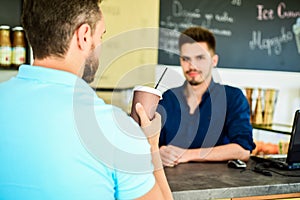 Man holds paper cup with coffee barista guy stand on background. Client got his drink. Have sip of energy. Man client