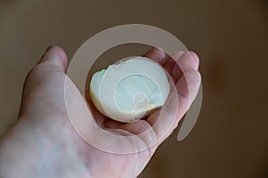 A man holds a peeled onion in his hand. Half of a white raw onion in the hand of a mature man. Selective Focus
