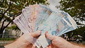 A man holds Philippine money bills in his hands.