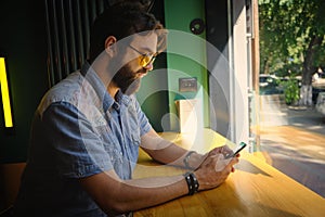 Man holds phone and chats online sitting in a cafe photo