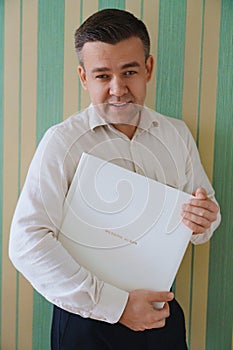 A man holds a photo book in a white leather cover