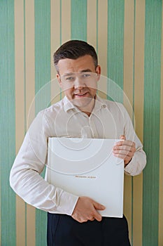 A man holds a photo book in a white leather cover