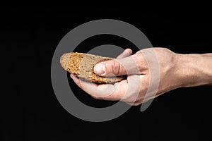 Man holds a piece of bread in his hand on black background