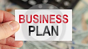 A man holds a piece of paper with the text: BUSINESS PLAN. Business and finance concept