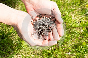 Man holds a pile of screws in hands