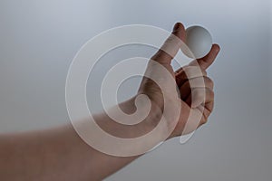 Man holds pingpong ball in a hand - grey background