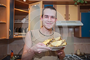 A man holds a plate of pineapples, cuts pineapple in the kitchen and ate