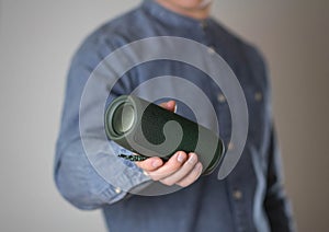 A man holds a portable speaker. Close up