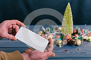 A man holds a postcard on a background with decoration on a wooden table. Festive composition for new year and christmas