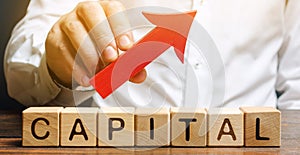 Man holds red arrow up above word Capital. Increase investment and foreign capital in the national economy. Improve business