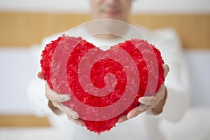 A man holds a red heart in his hands. Man shows a heart sign. Concept: love, valentines day, heart disease