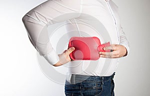 A man holds a red heating pad with water near the side of his back. The concept of treatment of sprains, hypothermia of photo