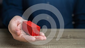 A man holds a red shipping containers in his hand. Cost savings due to bulk purchases or shared shipping expenses. Retailers and photo