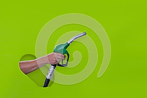 Man holds a refueling gun in his hand for refueling cars isolated on a green background. Gas station with diesel and gasoline fuel