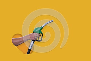 Man holds a refueling gun in his hand for refueling cars isolated on yellow background. Gas station with diesel and gasoline fuel