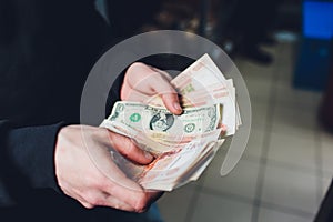 A man holds rubles and dollars in his hand, a businessman holds money in his hand.