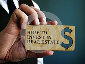 Man holds sign How to Invest in Real Estate