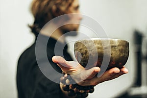 A man holds a singing bowls on his outstretched hand. Music of Tibetan singing bowls.