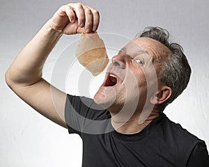A man holds a slice of Parma ham, Italy in his hand near his mouth as he is about to eat it voraciously