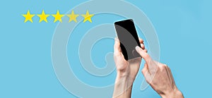 Man holds smart phone in hands and gives positive rating, icon five star symbol to increase rating of company concept on blue