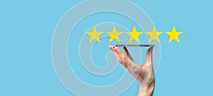 Man holds smart phone in hands and gives positive rating, icon five star symbol to increase rating of company concept on blue