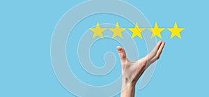 Man holds smart phone in hands and gives positive rating, icon five star symbol to increase rating of company concept on blue