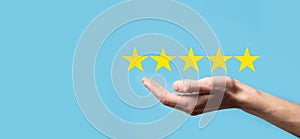 Man holds smart phone in hands and gives positive rating, icon five star symbol to increase rating of company concept on blue