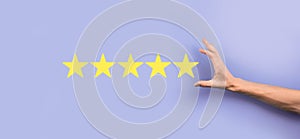 Man holds smart phone in hands and gives positive rating, icon five star symbol to increase rating of company concept on blue