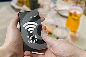 Man holds smartphone and is using free wifi in restaurant