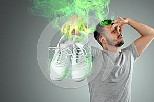 A man holds sneakers in his hands. Nasty smell. Stink legs, fungus on the legs