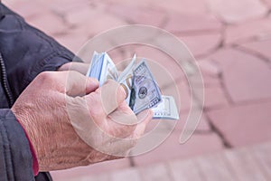 A man holds a stack of hundred-dollar bills in his hands