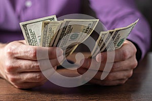 A man holds stack hundred-dollar bills in his hands close-up